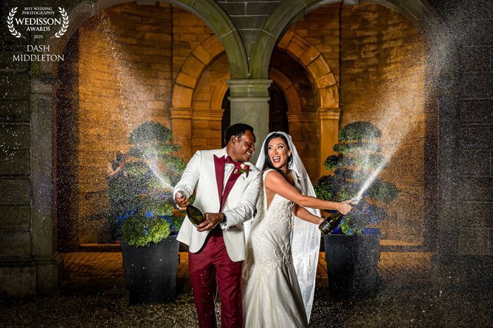 A bride and groom's joyous and energetic champagne moment, captured perfectly with luxury wedding photography at Lartington Hall